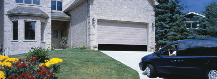 a Blcak minivan pulling into a house with the Garage door opening