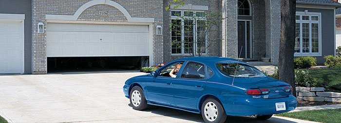 a Blue car pulling into a house with the Garage door opening